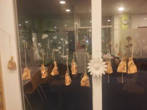 kleine Geschenkebeutel hängen an Wollfäden vor dem Fenster